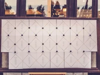 Seating plan colocado geométricamente sobre un marco con fondo metálico en una boda en Sevilla.